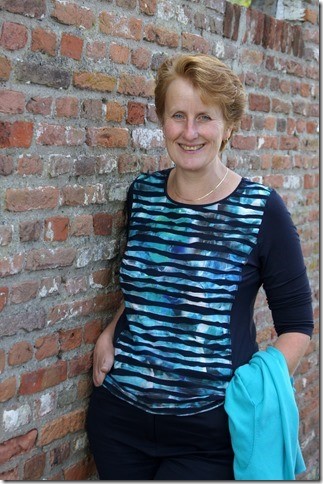 foto van notaris Anneke Bouwman die tegen een muur leunt en vriendelijk lacht