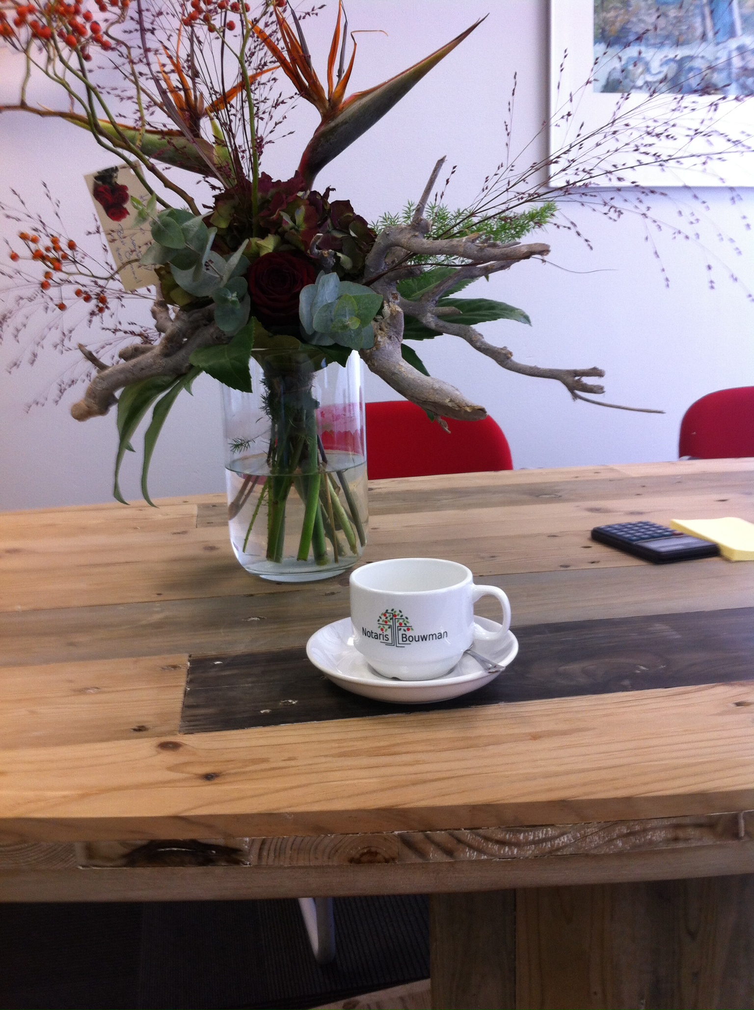 foto van een koffiekopje van notaris bouwman op een houten tafel achter het kopje staat een bouquet